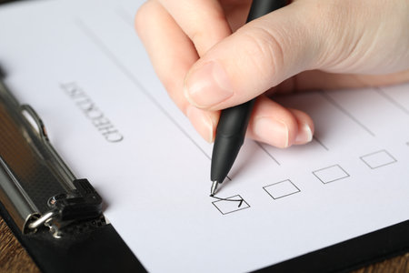 Woman checking box of Checklist at table, closeupの写真素材