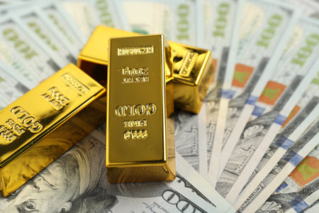 Shiny gold bars on dollar banknotes, closeup. Space for textの写真素材