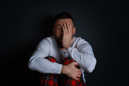 Fear of darkness. Scared man on black background