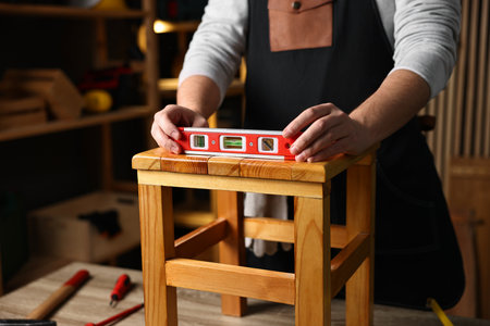 Repairman checking stool level at table in workshop, closeupの写真素材