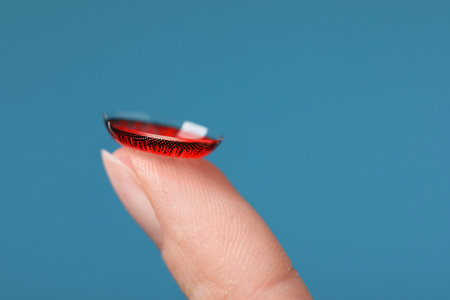 Woman with red color contact lens on light blue background, closeupの写真素材