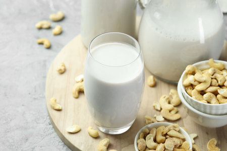 Fresh cashew milk in glass and nuts on gray table, closeupの写真素材