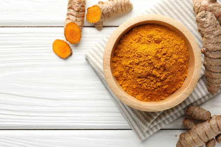 Aromatic turmeric powder and fresh roots on white wooden table, flat lay. Space for text