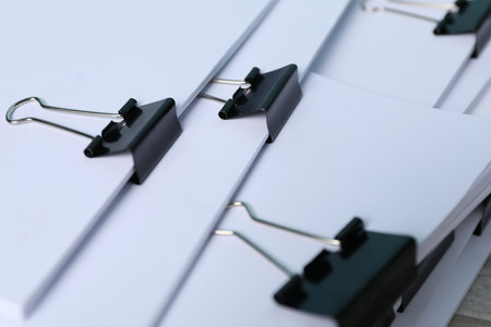 Binder clips with sheets of paper as background, closeupの写真素材