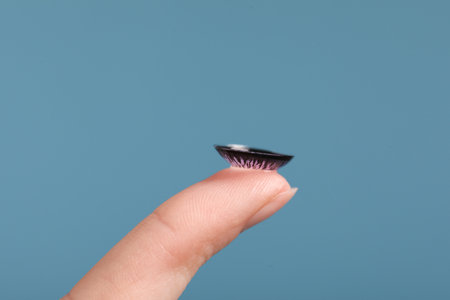 Woman with color contact lens on light blue background, closeupの写真素材