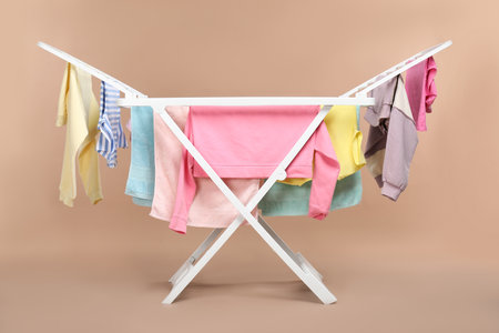 Drying rack with fresh clean laundry on beige backgroundの写真素材