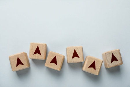 Wooden cubes with arrow on light background, top view