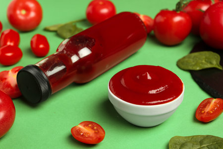 Ketchup, tomatoes and spinach on green background, closeupの写真素材
