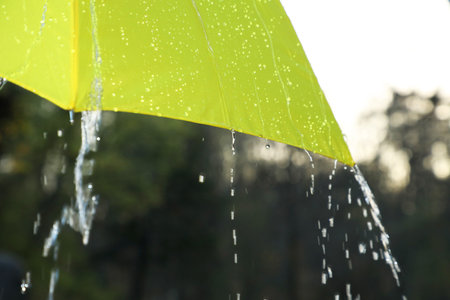 Open yellow umbrella under pouring rain outdoors, closeupの写真素材