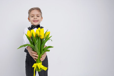 Cute little boy with bouquet of tulips on white background. Space for textの写真素材