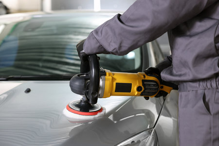 Man polishing car hood with orbital polisher indoors, closeupの写真素材