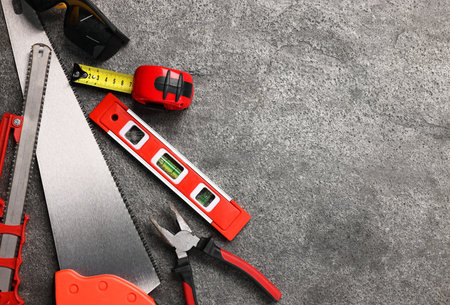Different construction materials and tools on gray table, flat lay. Space for text