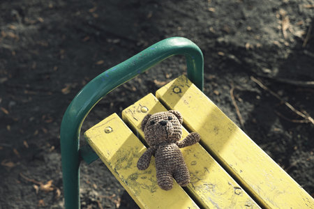 Lost knitted bear on bench outdoors, above view
