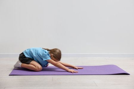 Cute little girl exercising on fitness mat indoors, space for textの写真素材