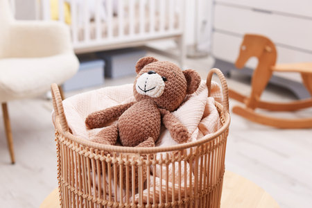 Wicker basket with blanket and toy bear in child's room, closeupの写真素材