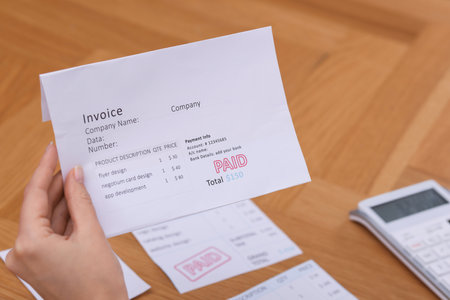Paying bills. Woman with different invoices and calculator at wooden table indoors, closeupの写真素材