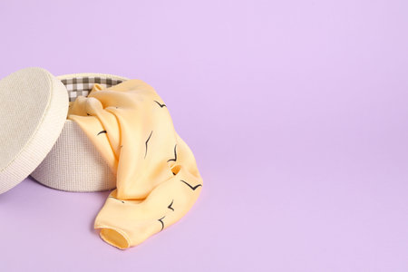 Beautiful scarf in box on lilac background. Space for textの写真素材