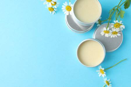 Lip balms and chamomile flowers on light blue background, flat lay. Space for textの写真素材