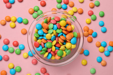 Tasty candies in bowl on pink background, top viewの写真素材