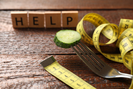 Squares with word Help, fork, slice of cucumber and measuring tape on wooden table, closeupの写真素材