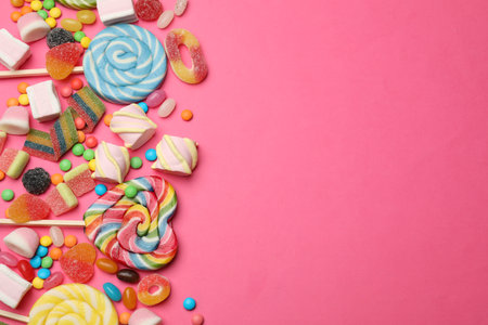 Different delicious candies and marshmallows on pink background, flat lay. Space for textの写真素材