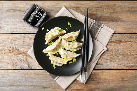 Delicious gyoza dumplings with chives served on wooden table, top viewの写真素材