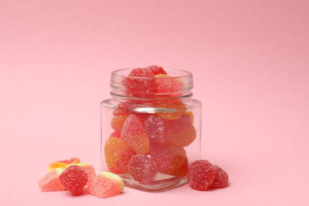 Tasty jelly candies in glass jar on pink background, closeupの写真素材