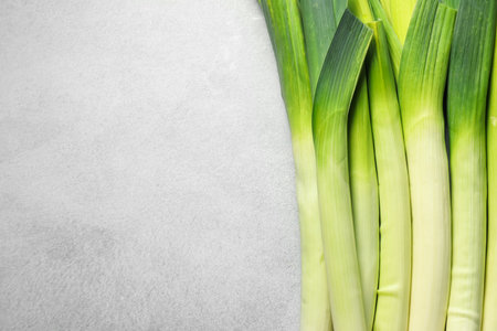 Fresh green leeks on light grey table, top view. Space for textの写真素材