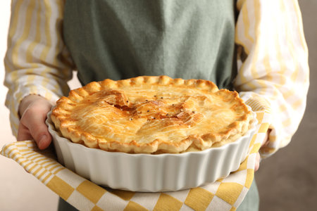 Woman with homemade pie on blurred grey background, closeupの写真素材