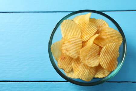Tasty potato chips on blue wooden table, top view. Space for textの写真素材