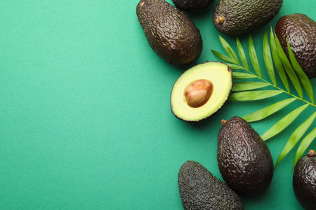 Fresh ripe avocados and leaf on teal background, flat lay. Space for text