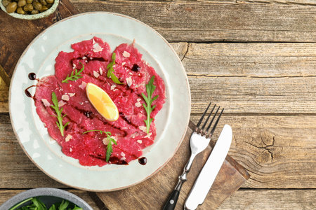 Delicious beef carpaccio served on wooden table, flat lay. Space for textの写真素材