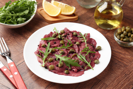 Fresh beef carpaccio with arugula and capers on wooden table, closeupの写真素材