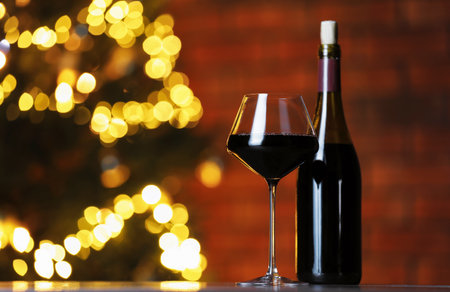 Tasty red wine in glass and bottle on table against blurred lights, space for text. Bokeh effectの写真素材