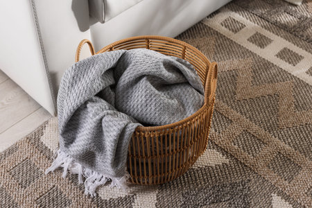 Wicker basket with gray blanket near sofa indoorsの写真素材