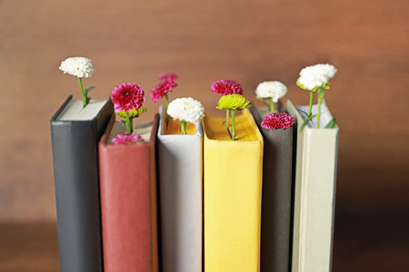 Different books with beautiful flowers on blurred background, closeupの写真素材