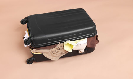 Packed suitcase full of clothes on beige backgroundの写真素材