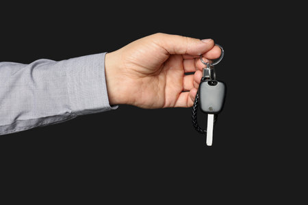 Woman with car key and keychain on black background, closeupの写真素材
