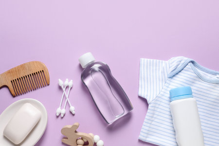 Baby oil, clothes and bath accessories on lilac background, flat layの写真素材