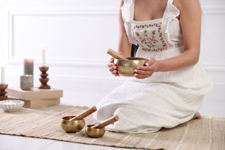 Woman with singing bowls on floor indoors, closeupの写真素材