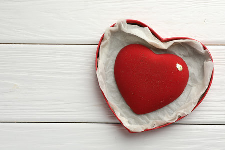 Heart shaped chocolate in box on white wooden table, top view. Space for textの写真素材