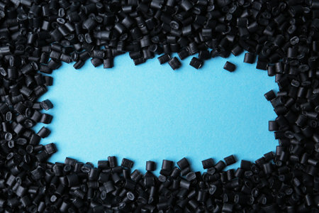 Frame of black plastic granules on light blue background, top view. Space for textの写真素材