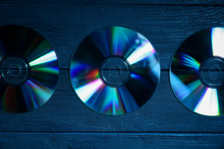 Shiny compact discs on wooden background, flat layの写真素材