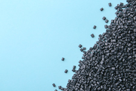 Pile of black plastic granules on light blue background, top view. Space for textの写真素材