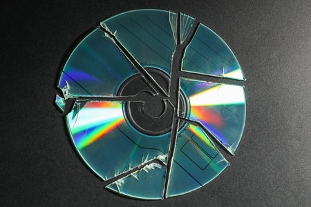 Broken compact disc on black background, top viewの写真素材