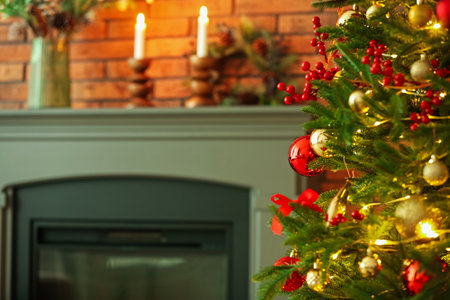 Beautiful decorated Christmas tree near fireplace at home, closeup. Space for textの写真素材