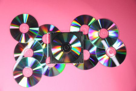 Many shiny compact discs on pink background, flat layの写真素材