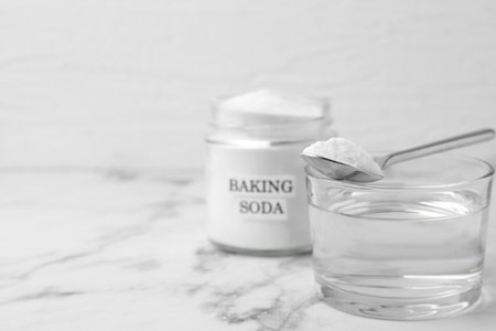 Glass of water and baking soda on white marble table, selective focus. Space for textの写真素材
