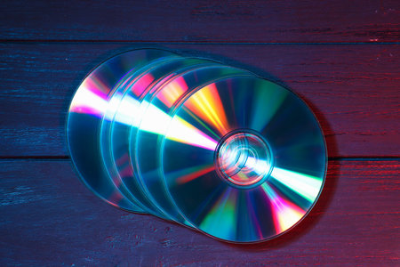 Shiny compact discs on wooden background, top viewの写真素材