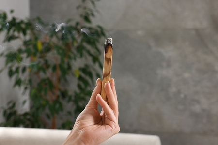 Woman with smoldering palo santo stick at home, closeupの写真素材
